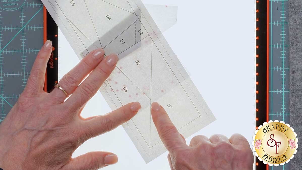 fpp_series_4_june_checking_points.jpg A fabric piece flipped open over a light pad during a placement check, showing whether it covers the acute angle.