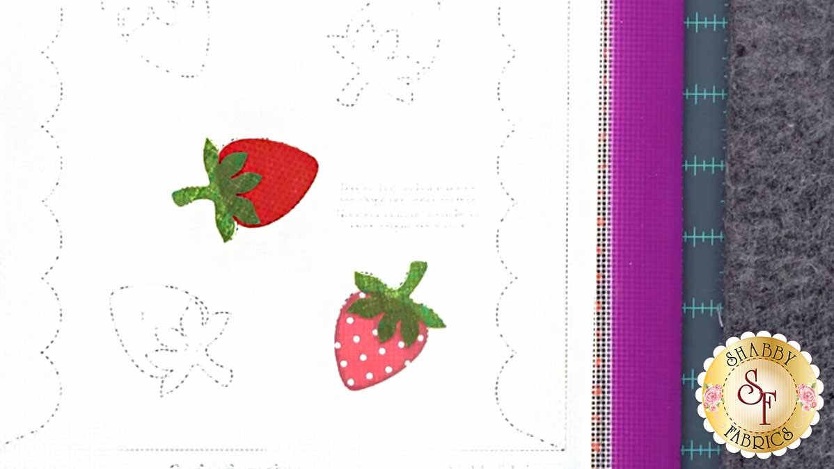 sew_cute_june_strawbz.jpg A strawberry applique shape being positioned on the Appli-Fuse Mat over a lit applique diagram.