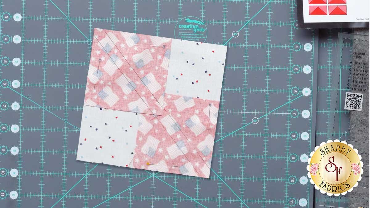 Two marked squares pinned right sides together into opposite corners of the large background square.