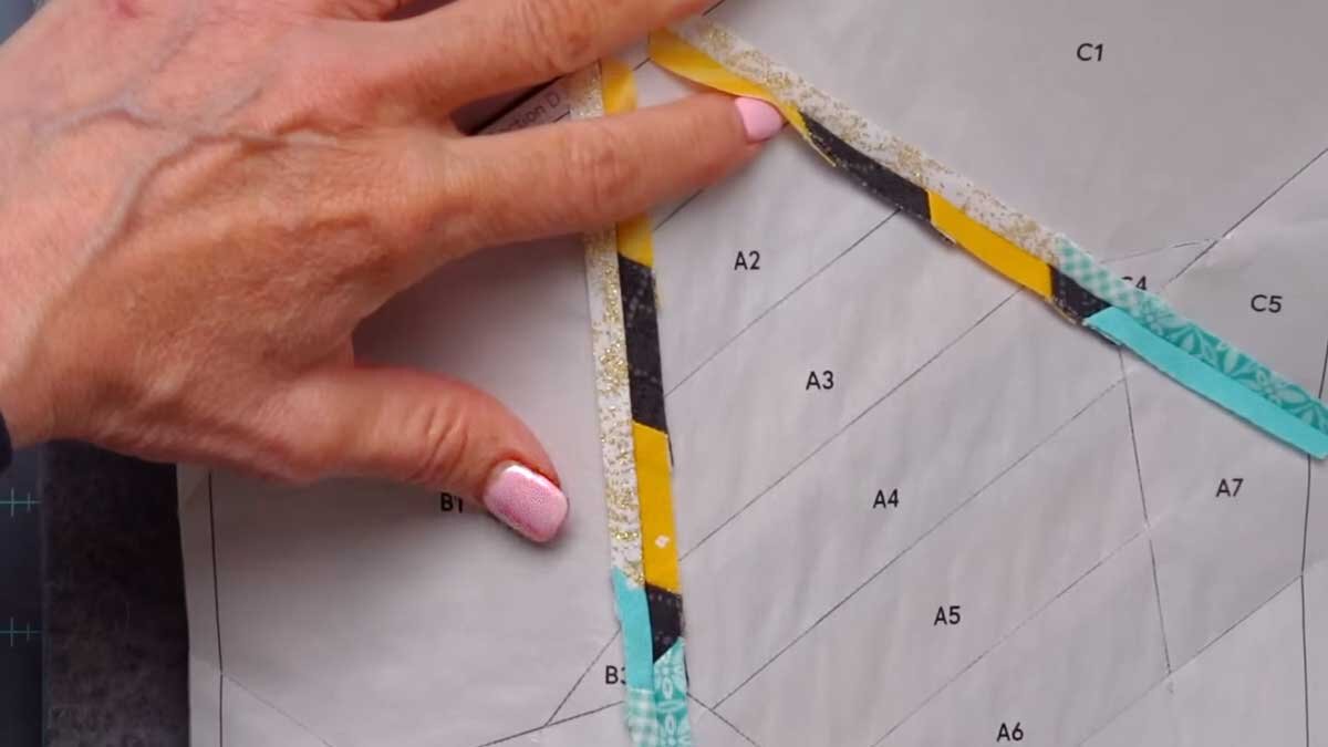 fpp_august_4_pressing_open.jpg A border strip pinned to the edge of the block, with the printed quarter inch line still visible on the foundation paper.