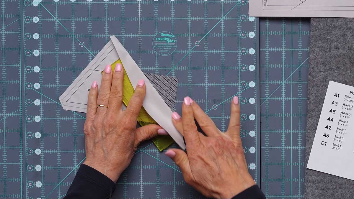 fpp_august_4_folding.jpg The Add-a-Quarter Plus ruler with its lip locked into the folded paper edge, positioned to trim the fabric.