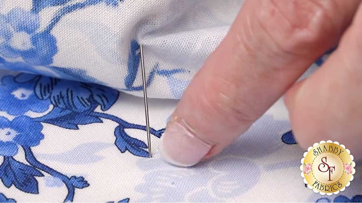 keyboard_kaleidoscope_bom_pointing_to_needle.jpg A flower head pin held perpendicular through an identical point in the design as fabric layers are stacked onto it.
