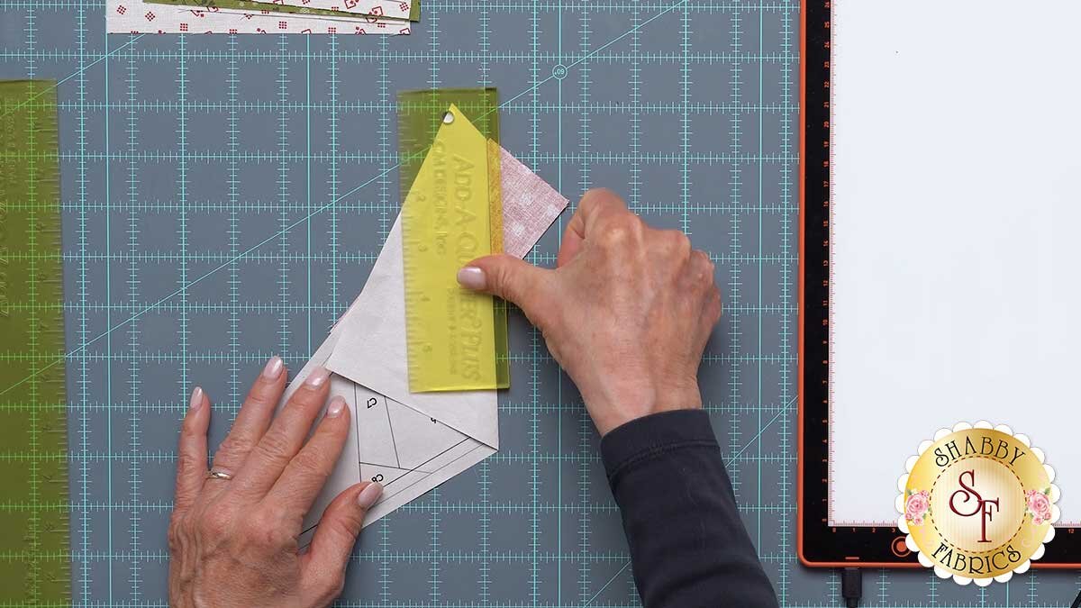 fpp_september_1200x675_ledge_ruler.jpg The Add-A-Quarter Plus ruler with its ledge locked against the folded paper edge, ready to trim the fabric.