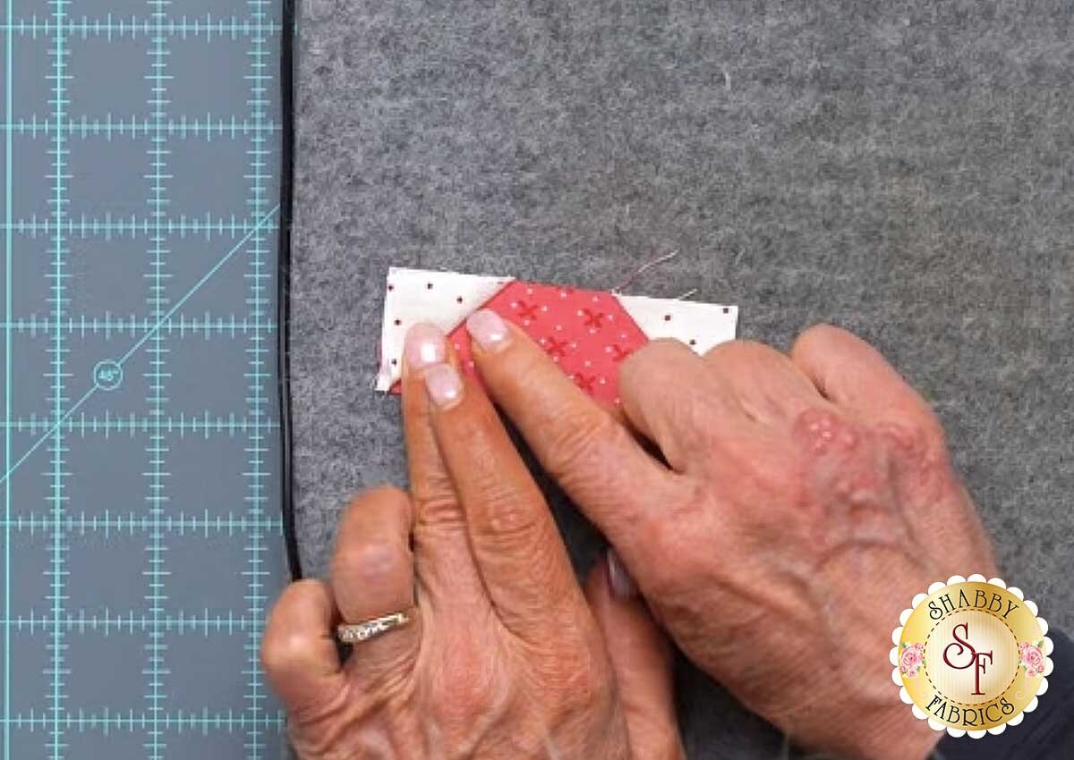 sew_cute_runner_september_wonky_crease.jpg A stitch-and-flip corner pressed open toward the cream, with the excess fabric still attached underneath.